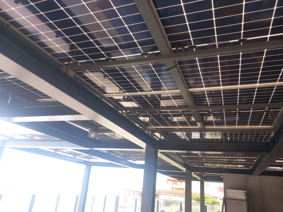 Vista por baixo da pérgola — perfis de aço lacado e painéis solares